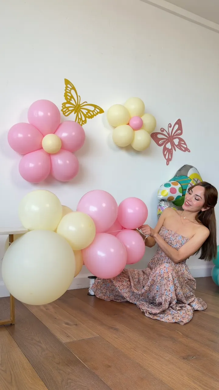 Ariane creando una guirnalda con globos rosa, crema y verde menta